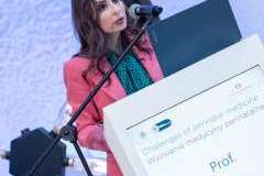 kobieta stoi przy mównicy i mówi przez mikrofon