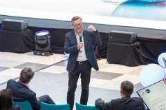 uczestnicy wydarzenia słuchają mężczyzny mówiącego przez mikrofon