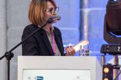 kobieta stojąca przy mównicy i mówiąca przez mikrofon