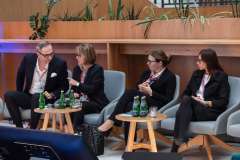 trzy kobiety i jeden mężczyzna siedzą na fotelach i rozmawiają