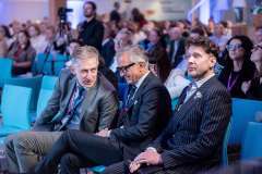 uczestnicy konferencji siedzą na auli konferencyjnej, w pierwszym rzędzie dwóch mężczyzn rozmawia