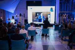 uczestnicy konferencji słuchają wykładu i oglądają film na ekranie