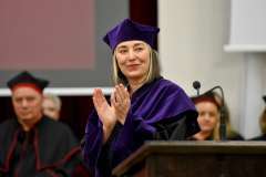 Uroczystość absolutorium. Kobieta ubrana w togę uśmiecha się i klaszcze