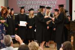 Wręczenie dyplomów studentkom ubranym w togi i biretki
