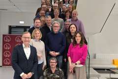 Grupa kilkunastu osób stojących na schodach w budynku, pozujących do wspólnego zdjęcia