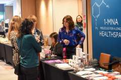 grupa kobiet rozmawia przy stoisku promocyjnym