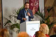 uczestnicy konferencji słuchają mężczyzny stojącego przy mównicy