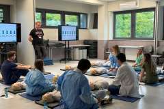 Grupa młodych osób podczas warsztatów siedzą przy fantomach do RKO