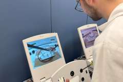 Młody mężczyzna w fartuchu lekarskim w trakcie ćwiczeń laparoskopem