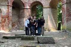 Grupa młodych ludzi stojących przed ruinami budynku