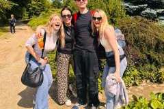 Trzy młode kobiety i jeden mężczyzna stoją na ścieżce w parku i uśmiechają się