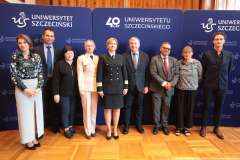 Grupa stojących osób na tle ścianki promocyjnej Uniwersytetu Szczecińskiego
