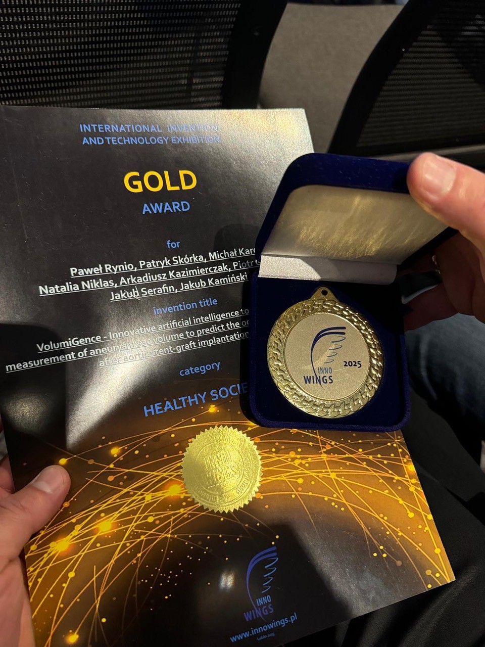 dyplom i złoty medal trzymane w rękach